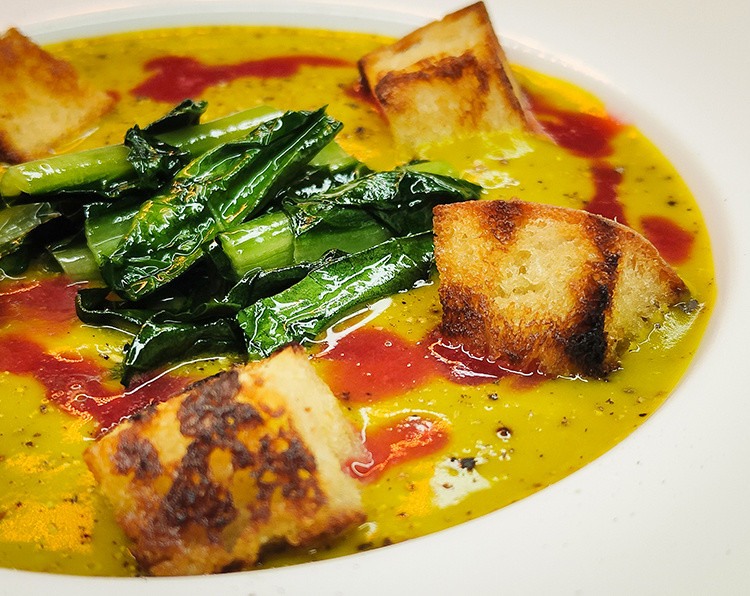 Vellutata di zucca con cicoria saltata, salsa di lamponi e pane croccante al burro